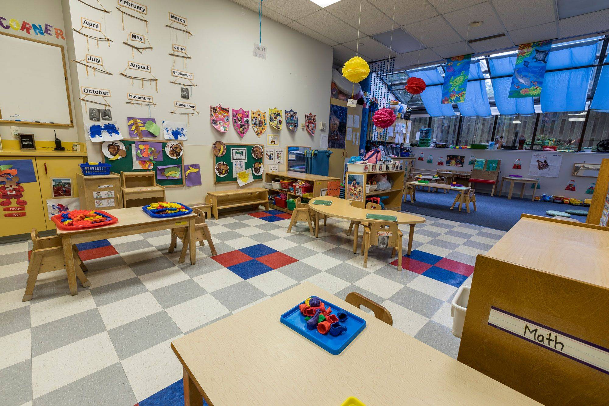 Photo of the older toddler classroom at Lakewood Child Care Center with dedicated table areas in the front of the room