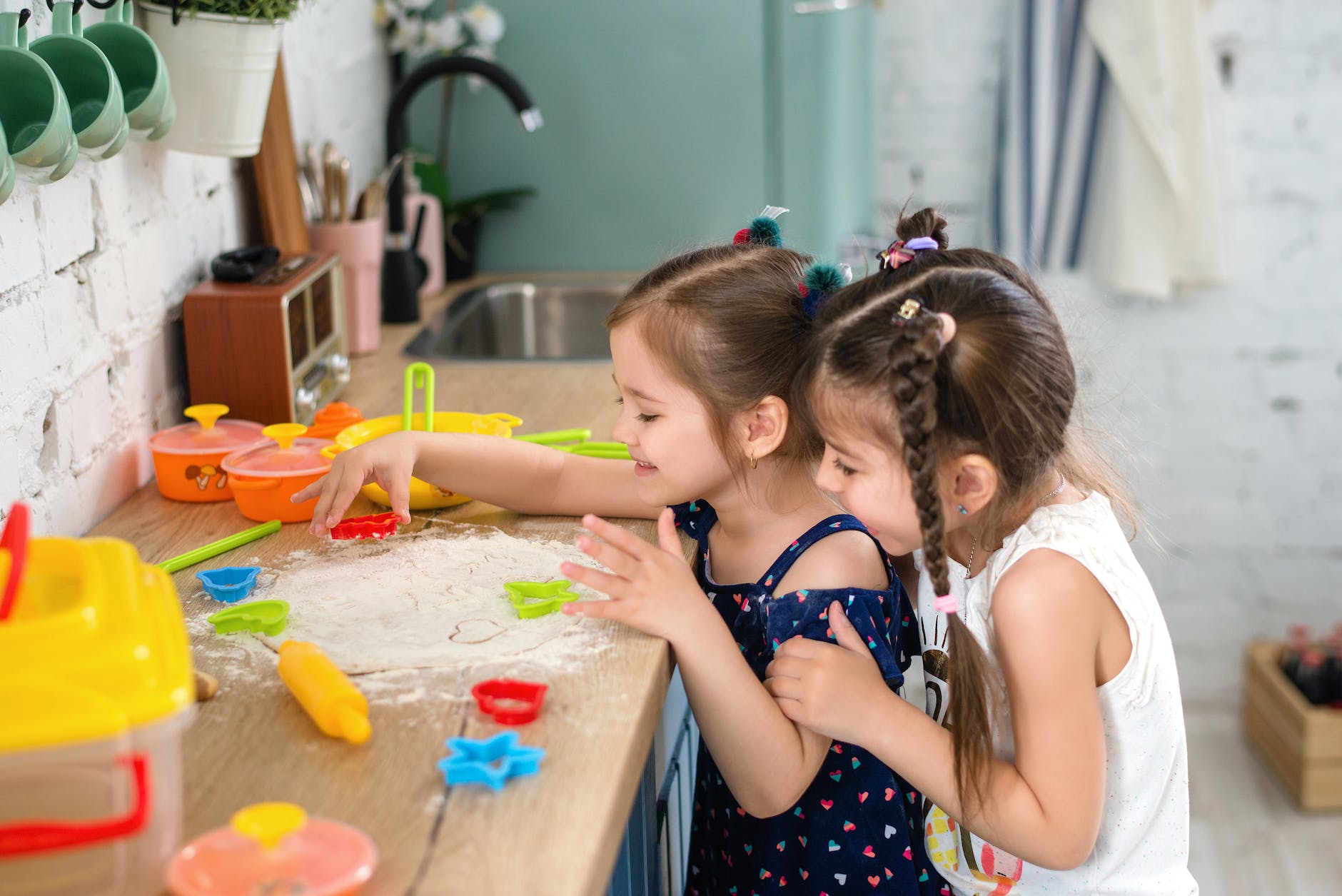 two girls playing with flour on a wooden kitchen counter