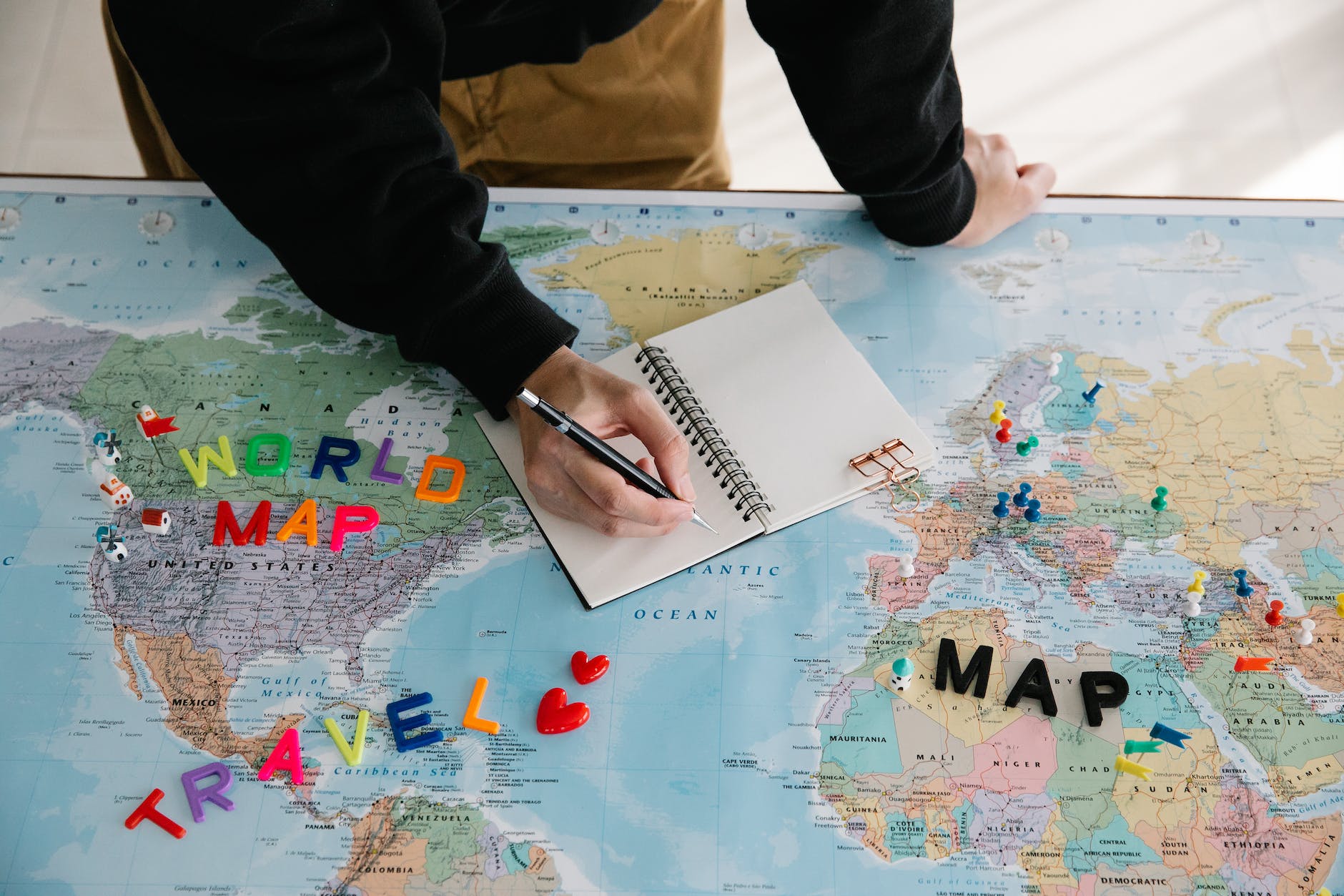 person writing on a notebook place on a world map