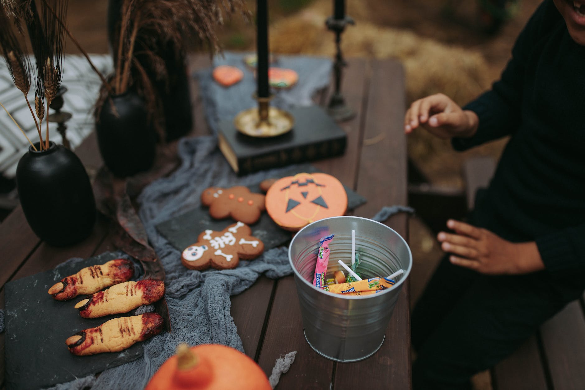 a person sitting at a table with halloween decorations and a bucket of candies