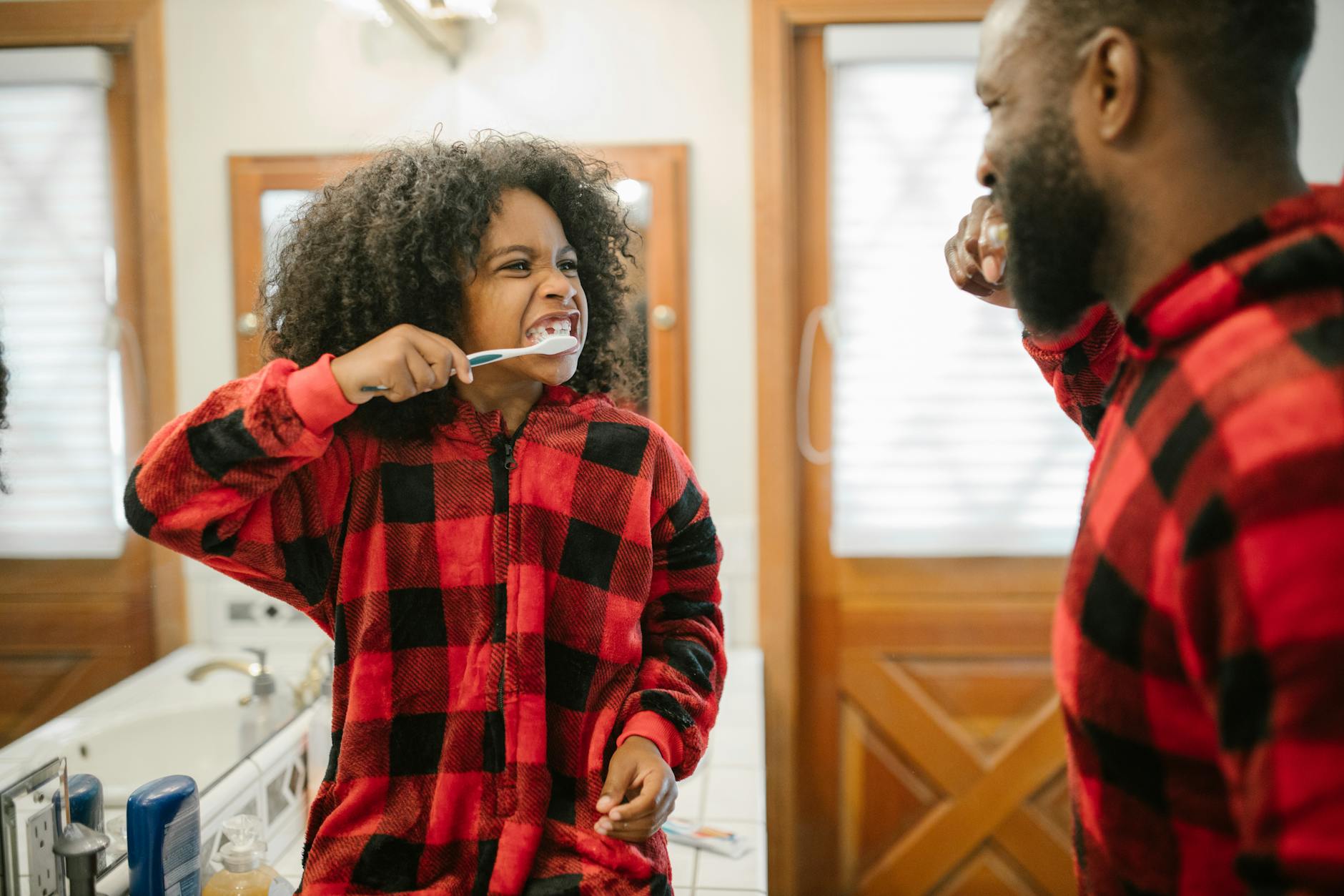 girl cleaning teeth with father supervision