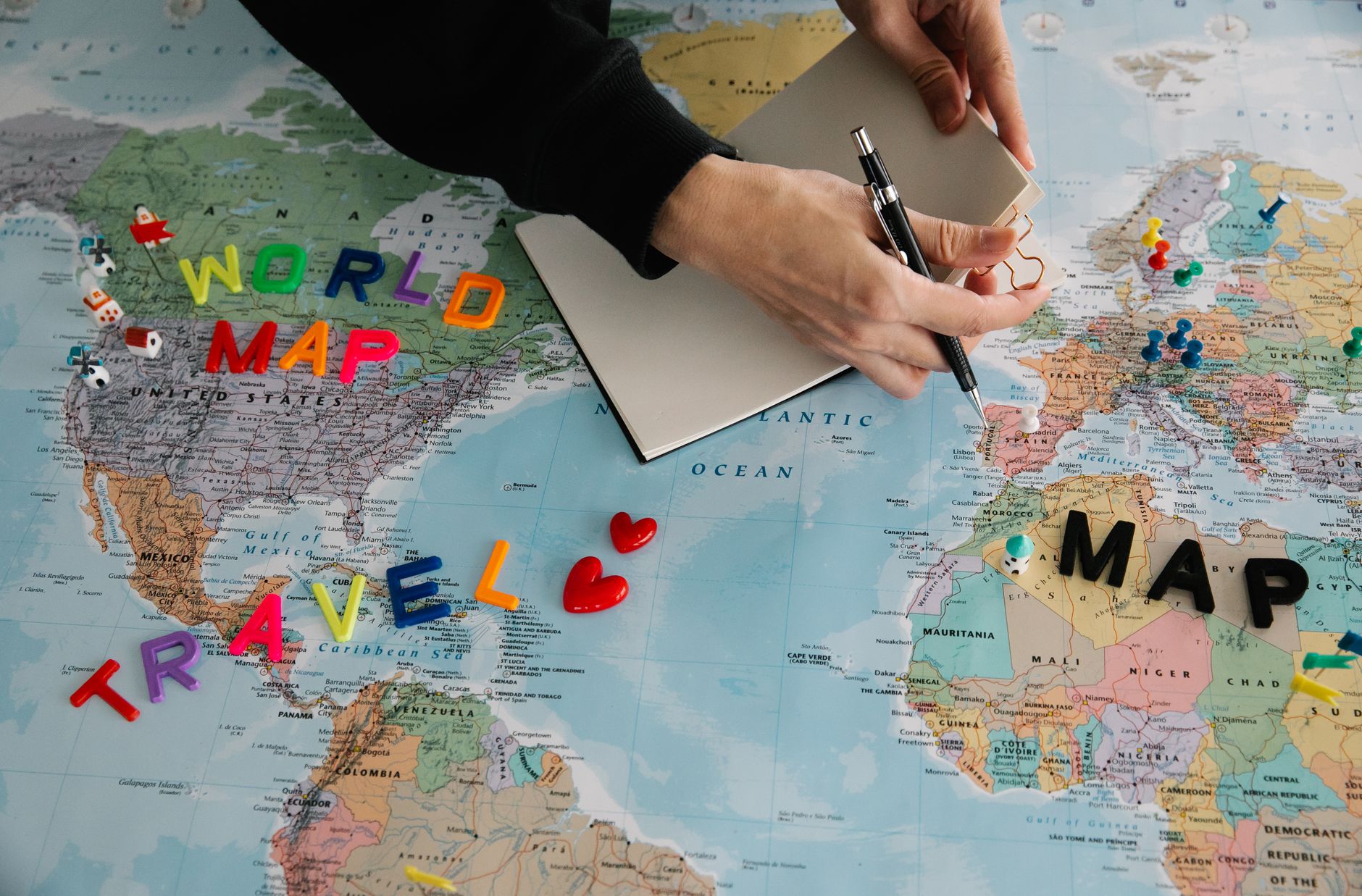 unrecognizable person planning travel on world map
